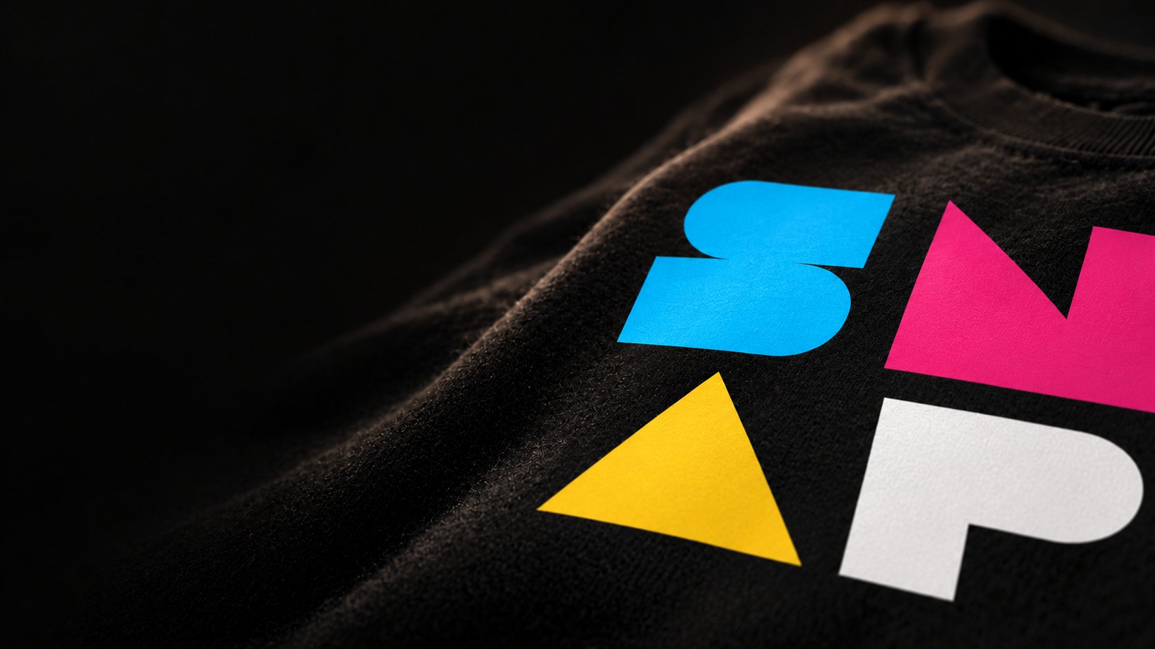 The SNAP logo printed in cyan, magenta, yellow and white on a black tee